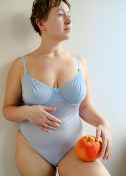 Curvy Woman in Blue Bodysuit Holding Grapefruit