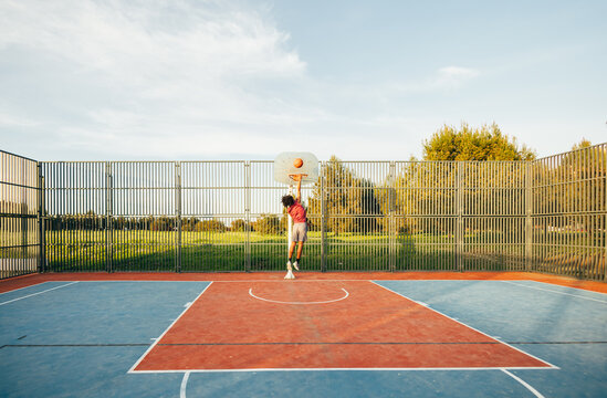 Basketball dunk on outdoor court beneath blue sky