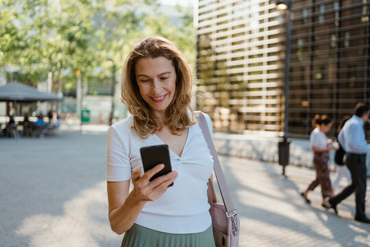 A woman uses a smartphone while walking in the city