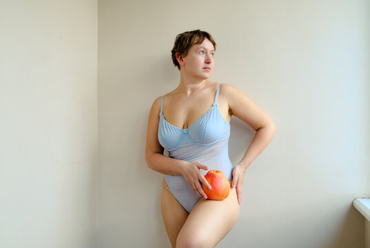 Curvy Woman in Blue Bodysuit Holding Grapefruit