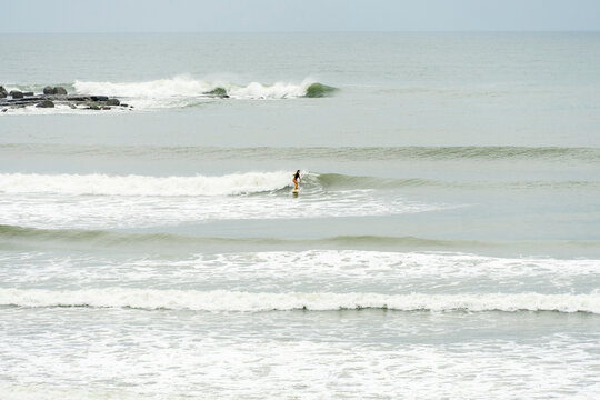 Woman surfing small wave at Angourie Point on overcast day