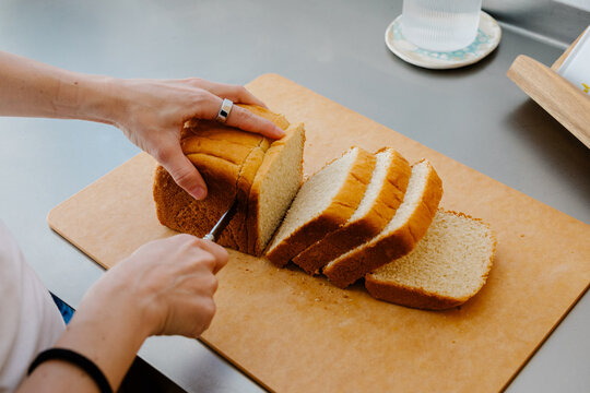 Unknown woman&rsquo;s hands cutting a bread loaf into pieces