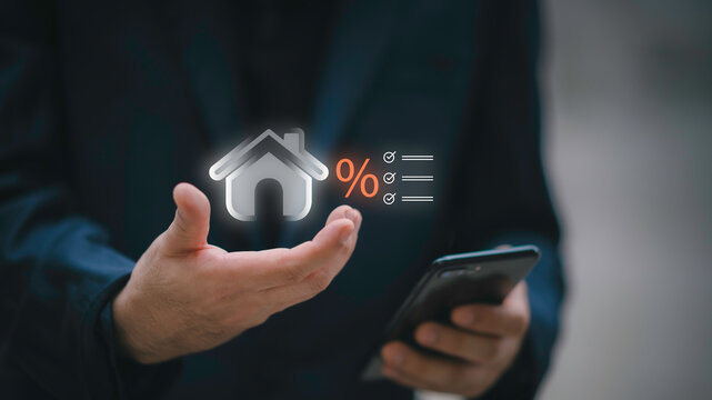 Businessman using telephone and laptop with house interest rate icon. Concept of real estate tax, mortgage loan calculation, financial planning, and home property investment.