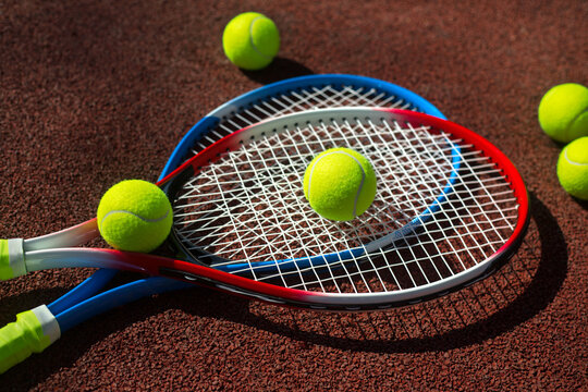 Two tennis rackets and five balls on a tennis court.