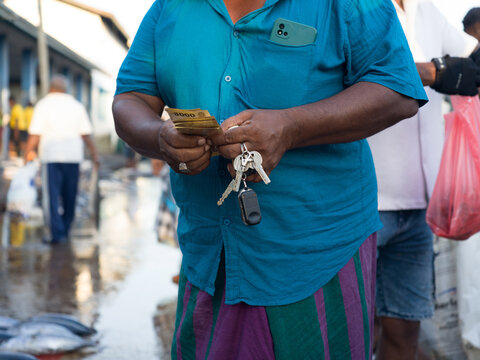 Market Scene With a Person Holding Cash and Keys in a Vibrant Area
