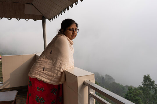 Indian woman looking outwards from the house in a mountain area