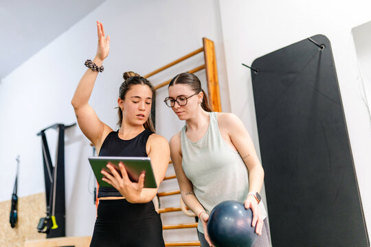 Personal trainer explaining workout plan using digital tablet