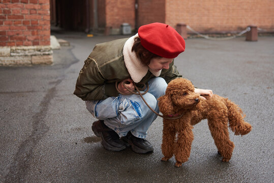 Woman interacts with dog in outdoor area in a city setting