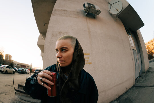 Person Holding a Drink Outside a Building During Sunset