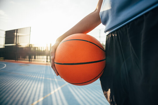 Basketball in hand on sunlit outdoor court