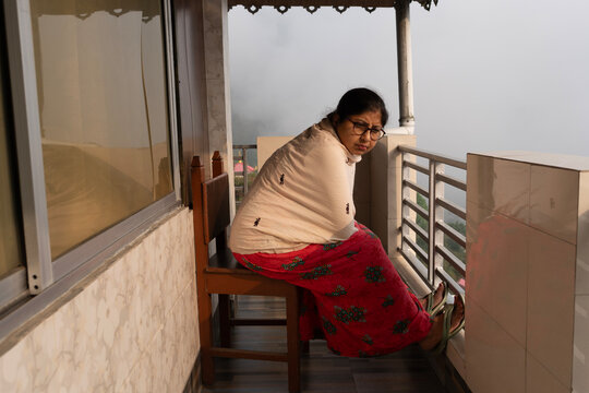 Indian woman looking outwards from the house in a mountain area