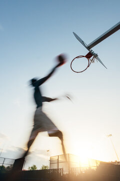 Basketball player dunking in silhouette at sunset