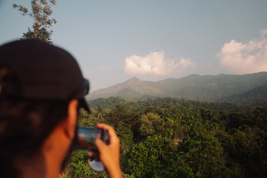 Person Taking a Picture of a Mountain Landscape in Daylight