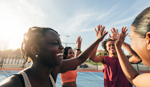 Group of friends celebrating on a sunny basketball court