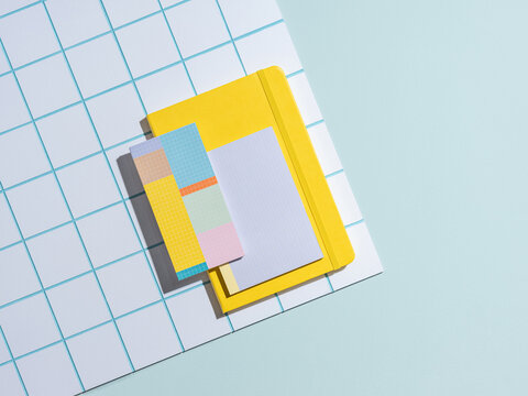 Bright yellow notebook and colorful sticky notes arranged on a blue