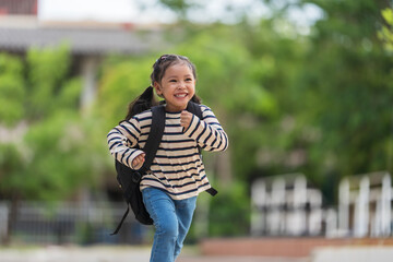 Fototapeta premium Cheerful student with backpack running happily on her way home from school