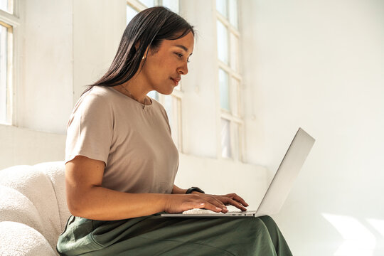 Brunette Woman Working on Laptop in Bright White Studio