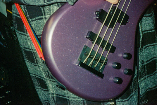 Purple Bass Guitar Held Against Plaid Flannel Shirt at Rehearsal
