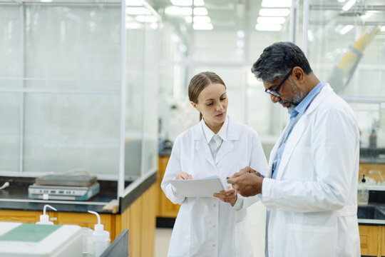 Two scientists young woman and Indian man in real laboratory
