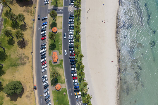 Rows of cars parked beside the road through a waterfront reserve