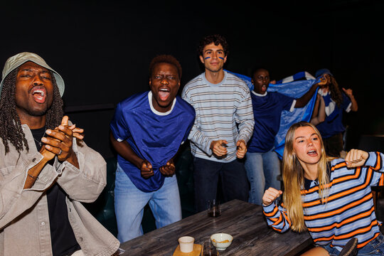 Sports fans passionately cheering watching game in bar