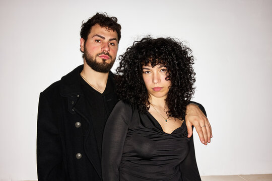 A man and a woman pose together in a studio setting