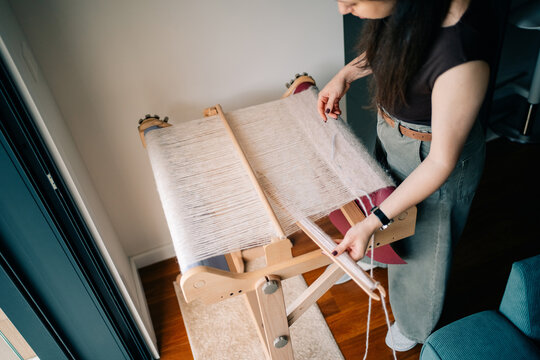 Woman Weaving on a Loom in Bright Indoor Space During the Day