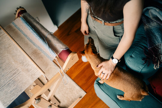 Woman Weaves Cloth While Dog Rests Nearby in Cozy Room Setting