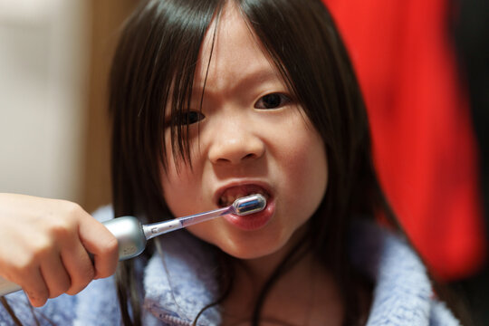 Young Girl Brushing Teeth with Electric Toothbrush