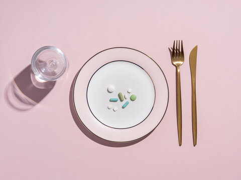 Pills on a plate with fork and knife, representing medication