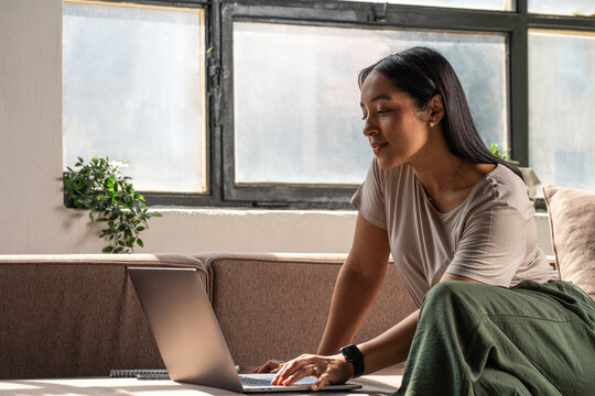 Woman Working Remotely on Laptop in Bright Room on the Couch
