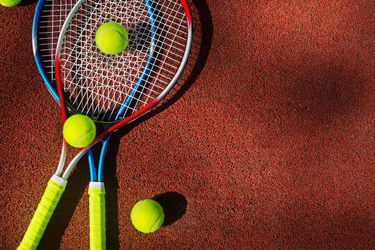 Two tennis rackets and three balls on a tennis court.