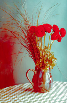 Red flowers in a vase on a checkered tablecloth with a blue wall