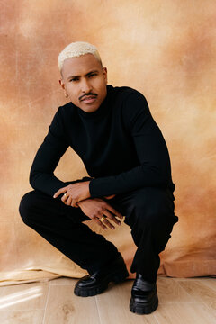 Man squatting in black turtleneck