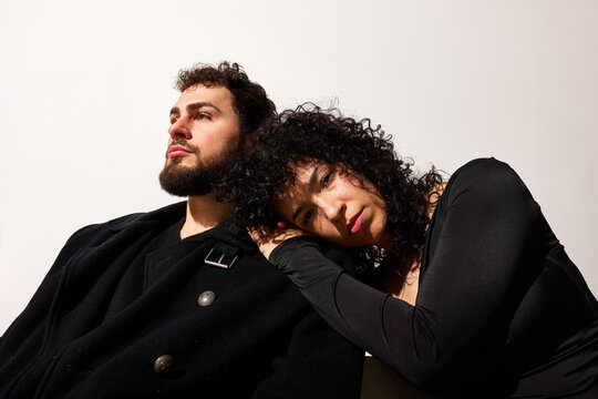 Couple sitting on a plain background with relaxed expressions