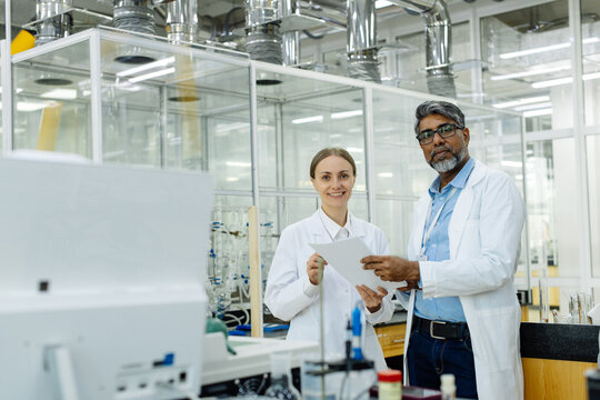 Two scientists young woman and Indian man in real laboratory