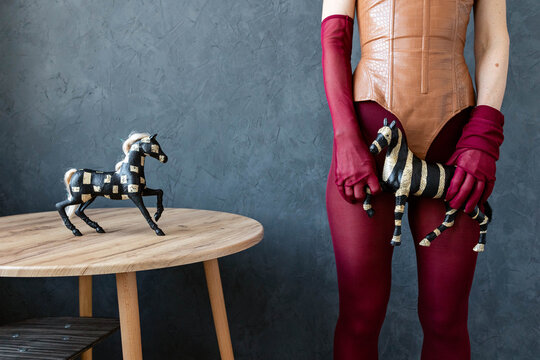 A woman poses with a toy horse in a studio.