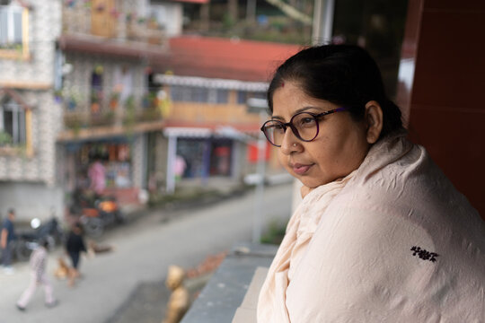 Indian woman looking outwards from the house in a mountain area