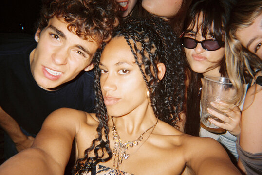 Group selfie with drinks at house party indoors