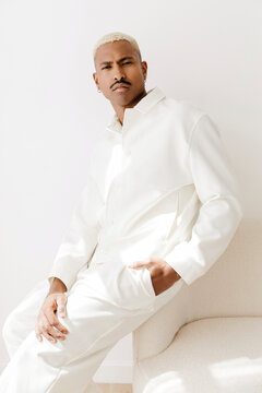 Man in white outfit against wall