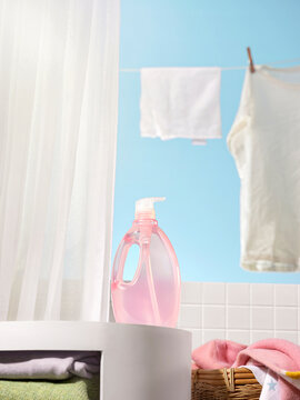 Pink liquid detergent bottle with laundry drying on a line