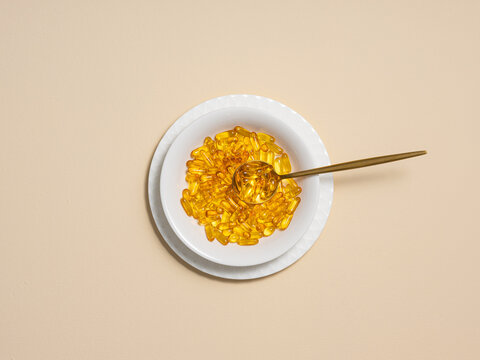 A bowl full of omega-3 capsules with a spoon, representing health