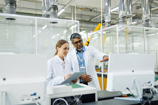 Young female scientist in white coat standing in laboratory