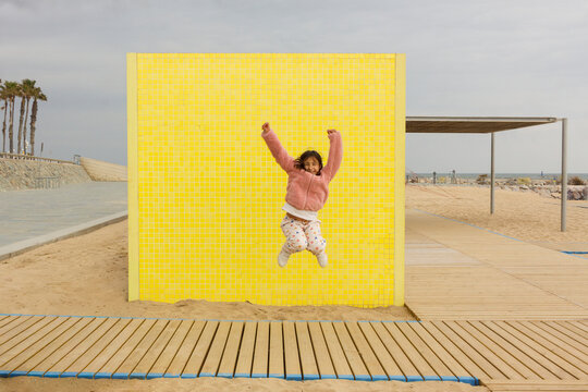 Girl Jumps in Front of Yellow Wall at Beach D