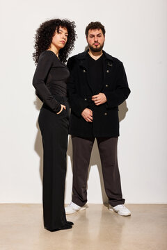 Couple stands together in modern space with neutral background