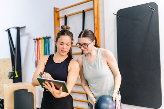 Personal trainer and woman discussing fitness routine using tablet