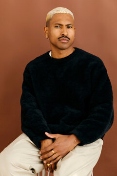 Man with blond hair posing on a stool