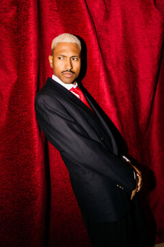 Stylish man in suit against red curtain