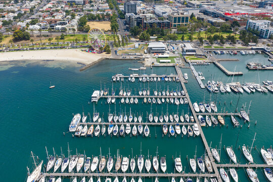 Rows of yachts lined up at piers off a city waterfront