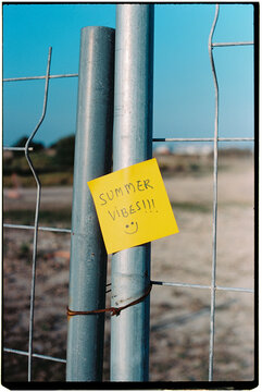 a sticky note with the text summer vibes on a fence, 35mm film